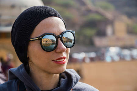 Portrait of a tourist girl. In her glasses is reflected Amer Fort. JAIPUR, INDIAの写真素材