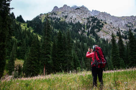 Trekking in the mountains. Girl takes a photo a landscape on a smartphone. Kazakhstan. Valley Left...