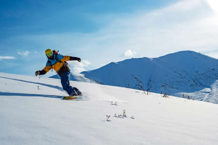 The guy is riding a snowboard. In the mountains in pristine snow. Mountains of Kyrgyzstanの写真素材