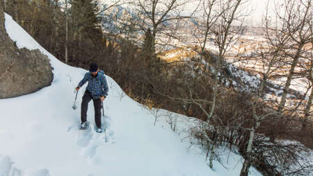 Hiker in the mountains walks on snowshoes. A man rises to the top. Winter mountain tourism. Kazakhstanの写真素材