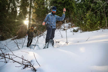 The guy with the girl are in the winter forest on snowshoes. Winter tourismの写真素材