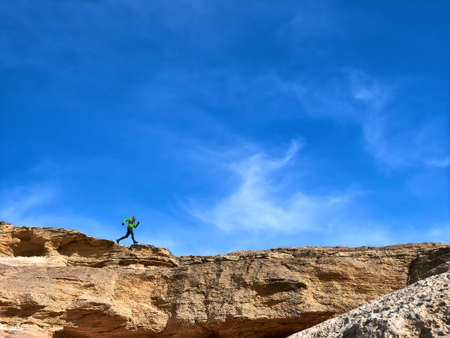 The athlete runs along the edge of a cliff against the sky. Trail Running. Mangistau Peninsula....