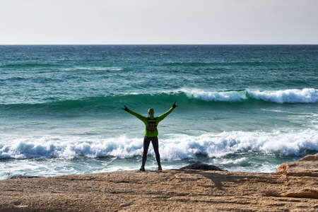 A male athlete with arms outstretched to the side is standing on the seashore. View from the back. Joy of victory. Trail Running. Mangystau Peninsulaの写真素材