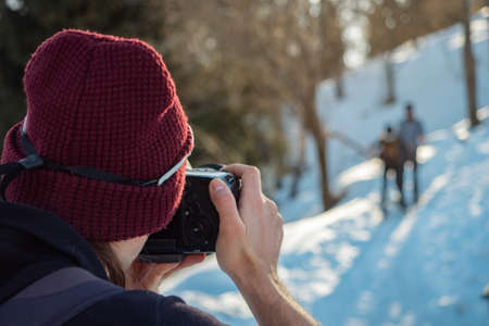 The guy shoots a photo of travelers in the winter. Back view. Close-upの写真素材