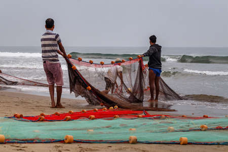 ARAMBOL, GOA, INDIA - JANUARY 17: Fishermen on the seashore pull out nets. Morning at sea. Arambol, Goa, Indiaのeditorial素材