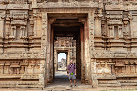 Male tourist at the entrance to the temple. The Group of Monuments at Hampi was the centre of the Hindu Vijayanagara Empire in Karnataka state in Indiaの写真素材