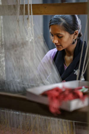 Ellora, Maharashtra, INDIA - JANUARY 15, 2018: Indian girl behind a traditional loom. Handmade traditional fabricのeditorial素材