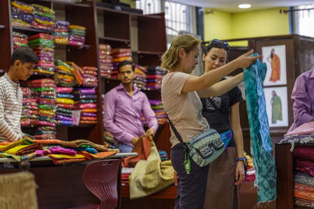 Ellora, Maharashtra, INDIA - JANUARY 15, 2018: European tourist girls in oriental traditional textile store. Girls buy a traditional scarf in the storeのeditorial素材