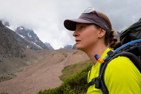 Portrait of a young tourist girl with a backpack in the mountains. Trekking in the high mountains....