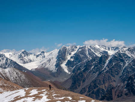 Hiker with a backpack in the high snowy mountains. Great views of the mountain peaks and the...