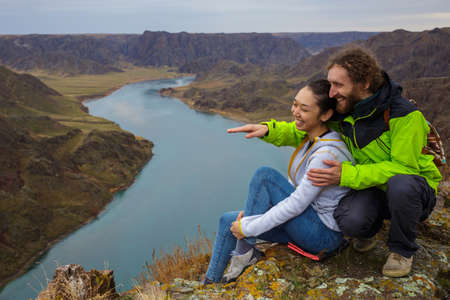 Young couple having fun outdoors near the beautiful river canyon. Young people are resting on the edge of the cliff. Spring landscape. The Ili River. Kazakhstanの写真素材
