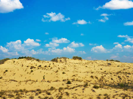 Athlete runs along the sandy desert. Desert trail running. A man in shorts and a T-shirt is running through the sandy wilderness.の写真素材