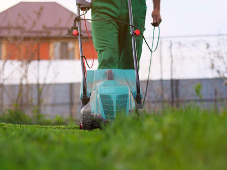 Mowing the lawn by lawnmower in the backyard. Garden background. Summer and spring season gardening backgroundの写真素材