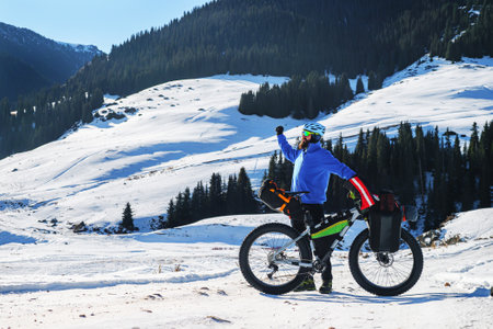 Male traveler on a fatbike in winter in the mountains. High-mountain plateau Turgen-Asy, Kazakhstanの写真素材