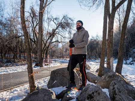 Bearded man in a winter park. Guy lover of nordic walking. Recreation fitness and healthy lifestyle outdoors in nature. Motivation and inspirational winter landscape.の写真素材