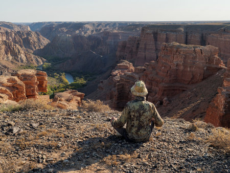 A tourist sits on the edge of a cliff overlooking the Charyn Canyon, Almaty region, Kazakhstanの写真素材