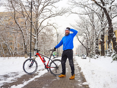 Smiling bearded man with a bicycle in a winter park. Active and healthy lifestyle in the city. Ecological transportの写真素材