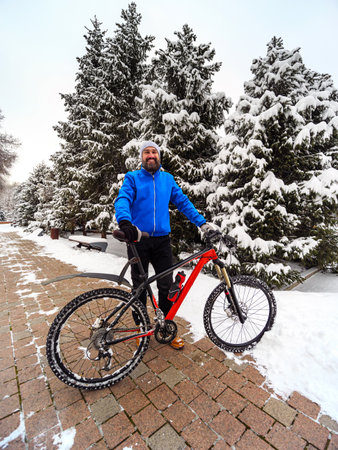 Happy bearded man with a bicycle in a winter city park. Active and healthy lifestyle in the cityの写真素材