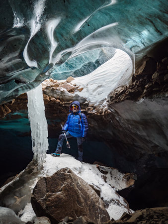 The traveler is in a mountain cave made of ice. Incredible adventures in the mountains. Bogdanovich Glacierの写真素材