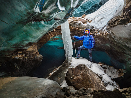 The bearded man is surrounded by bizarrely shaped blocks of ice that are a rich turquoise color. Incredible adventures in the mountains. Bogdanovich Glacierの写真素材