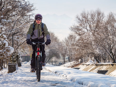 A man rides a bicycle on an icy sidewalk on a winter day. Active lifestyle in winterの写真素材