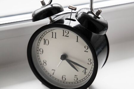 An alarm clock stands on a window in the morning light.の写真素材