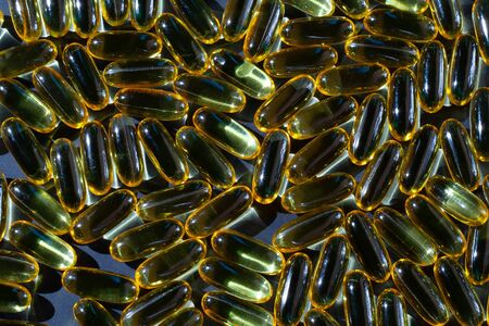 Omega-3 vitamins, fatty acids. Fish oil in yellow capsules on a black background.