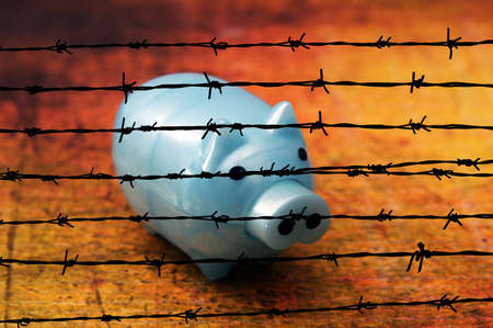 Piggy bank on grunge background against barbwireの写真素材