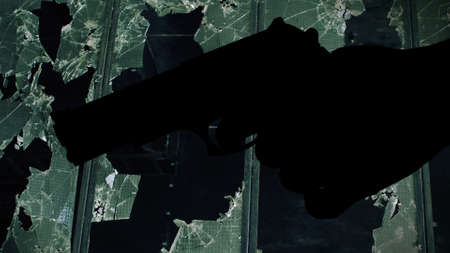 Gun silhouette against broken window crime conceptの写真素材