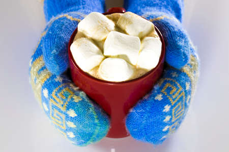 Top view of red cup of hot chocolate and marshmallows in female hand