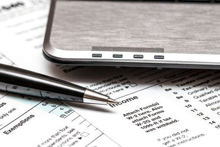 US 1040 tax form with pen and laptopの写真素材