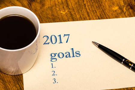 2017 list of goals on a sheet of paper, a wooden table with a Cup of coffeeの写真素材