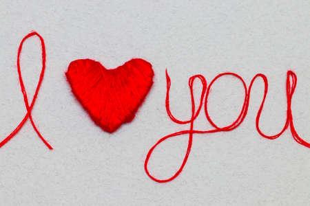 Love you words and heart symbol made of red thread on a white background for your Valentine's dayの写真素材