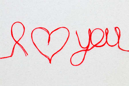 Love you words and heart symbol made of red thread on a white background for your Valentine's dayの写真素材