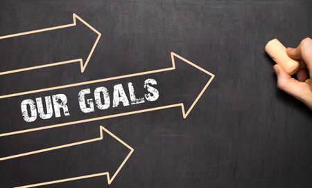 A businessman is drawing Our Goals concept with arrows on blackboardの写真素材