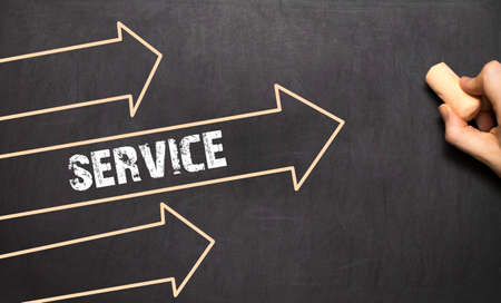 A businessman is drawing Service concept with arrows on blackboardの写真素材