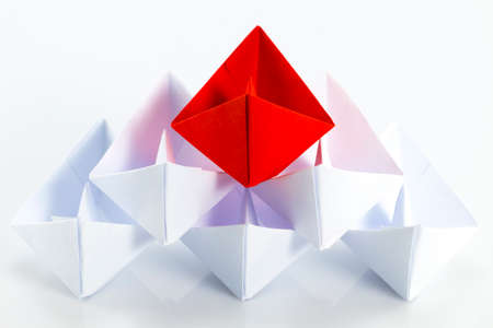 Leadership concept with red paper ship leading among white.