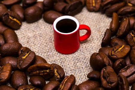 Heart of roasted coffee beans and a Cup on burlap backgroundの写真素材