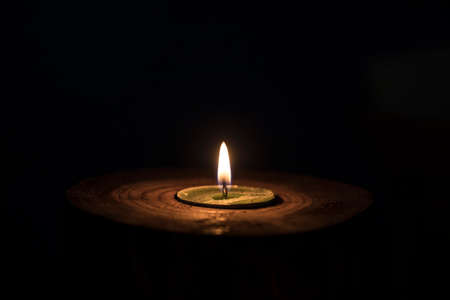 A white candle with dark background - in a wooden candlestick.の写真素材