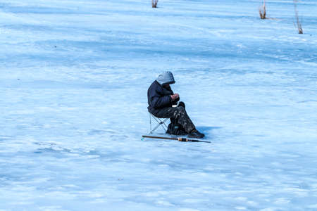 elderly man has been fishing in the winter on the lake.の写真素材