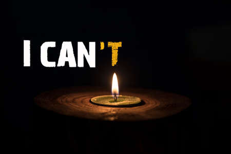 I can't - I can - white candle with dark background - in a wooden candlestick.の写真素材