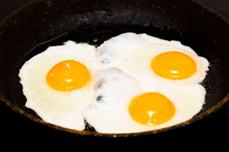 Fried eggs in a frying pan  for breakfast on a black background.の写真素材
