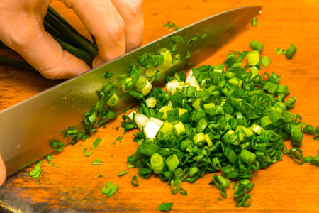 chopped green onions on wooden cutting board.の写真素材