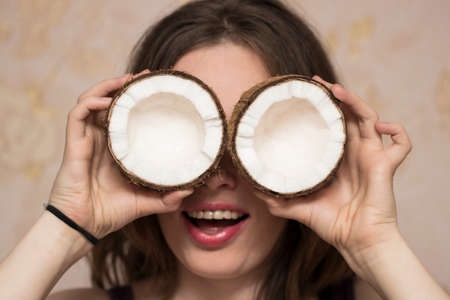 Portrait of cute girl with coconuts in near her eyes.の写真素材