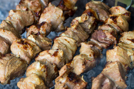Marinated shashlik preparing on a barbecue grill over charcoal. Shashlik or Shish kebab popular in...