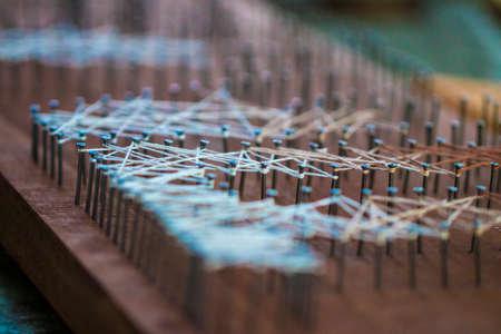 loose end tied up to wooden board with nails, handcraft textile concept.の写真素材