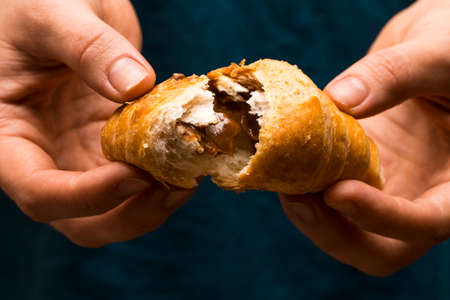 Female hands rip off a piece of fresh and tasty croissant.の写真素材