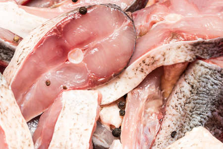 Raw steak of white fish and spices close-up.