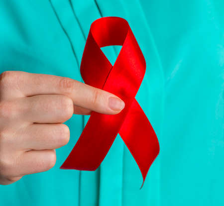 healthcare and medicine concept - female hands holding red AIDS awareness ribbon.の写真素材