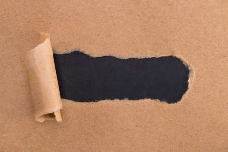 holes in brown paper with torn sides over paper background with space for text.の写真素材